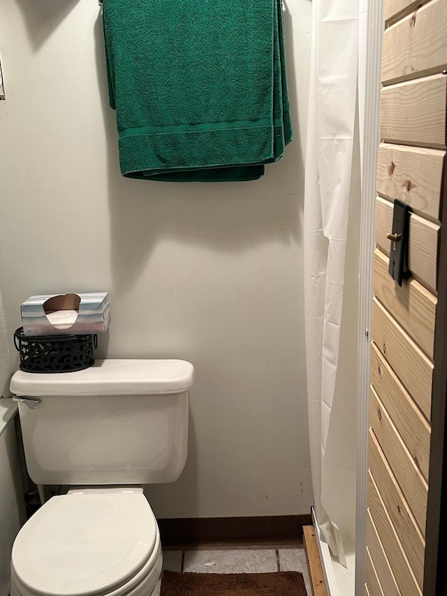 bathroom with toilet, tile patterned floors, and baseboards