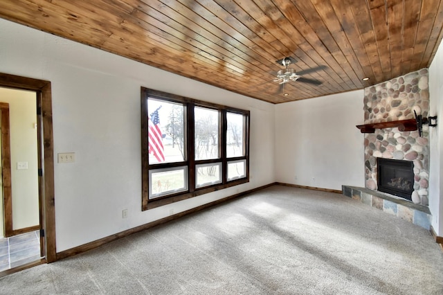 unfurnished living room featuring baseboards, a stone fireplace, ceiling fan, wood ceiling, and carpet flooring