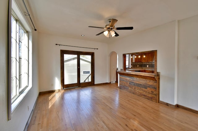 spare room featuring arched walkways, a healthy amount of sunlight, and baseboards