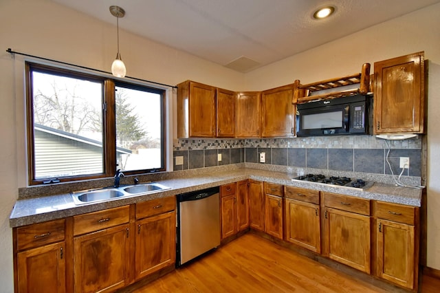 kitchen featuring light wood-style flooring, tasteful backsplash, brown cabinetry, a sink, and stainless steel appliances