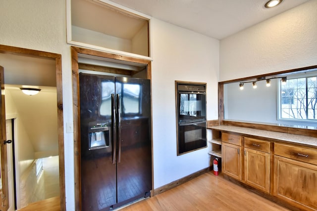 kitchen with brown cabinets, light wood finished floors, open shelves, and black appliances