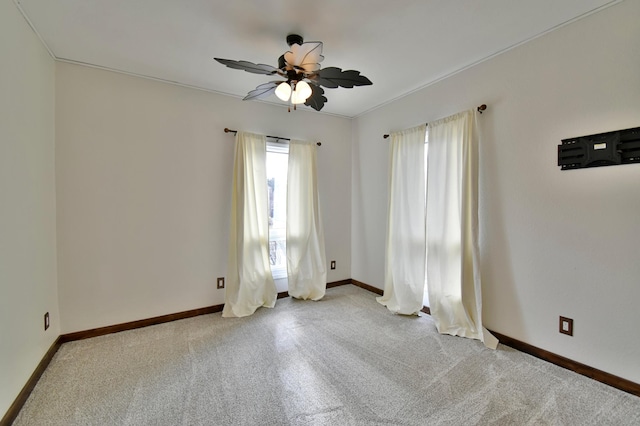 empty room featuring baseboards, a ceiling fan, and light colored carpet