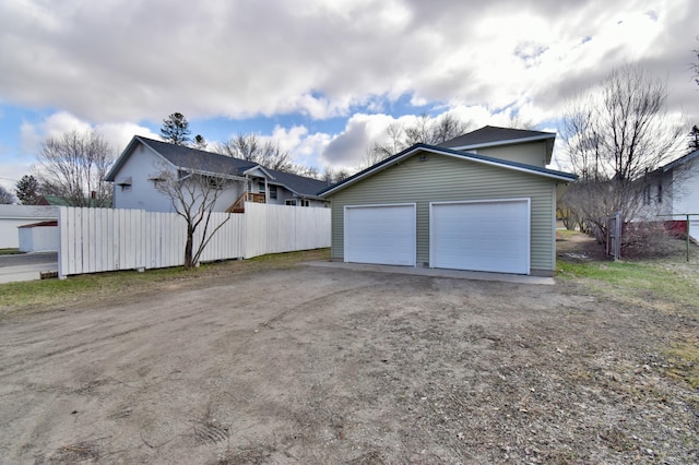 garage featuring fence and dirt driveway