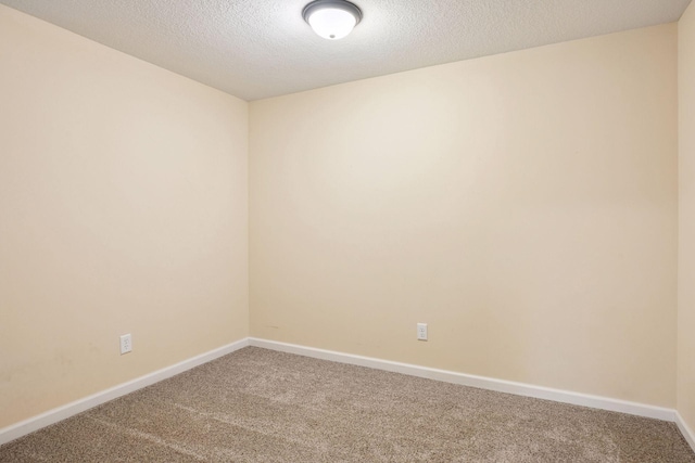 empty room with a textured ceiling, baseboards, and carpet