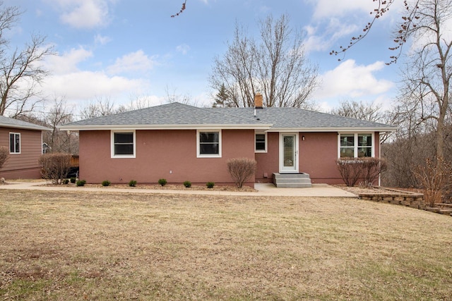 view of front facade featuring roof with shingles, a chimney, and a front yard