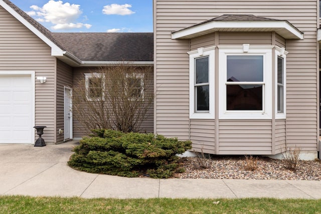 view of side of property with driveway, a shingled roof, and a garage