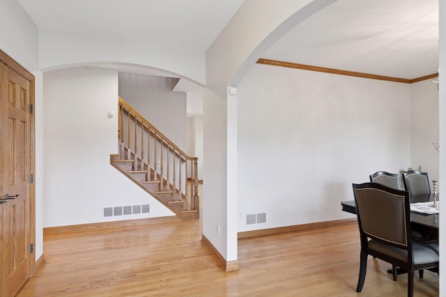 office area with baseboards, light wood-style flooring, visible vents, and ornamental molding