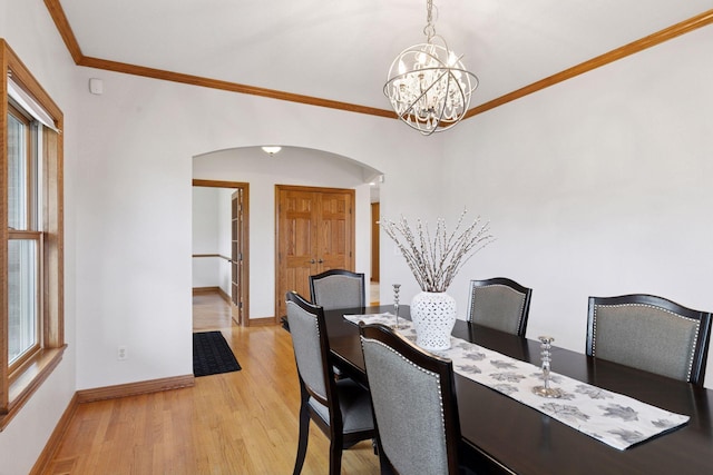 dining space featuring light wood finished floors, arched walkways, baseboards, a chandelier, and crown molding