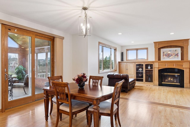 dining space with plenty of natural light, wood finished floors, a fireplace, and an inviting chandelier