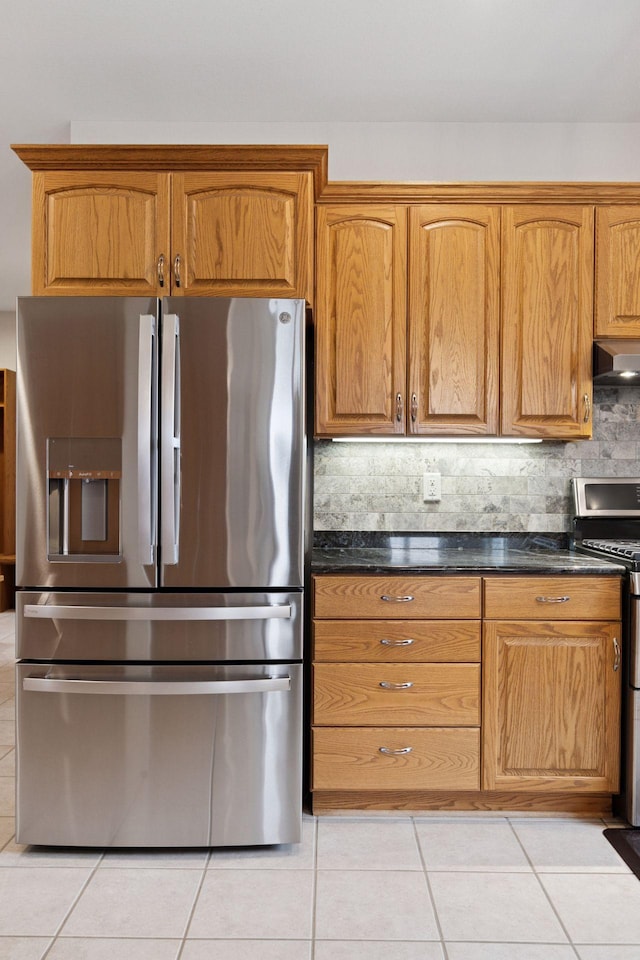 kitchen with light tile patterned floors, dark countertops, stainless steel appliances, and extractor fan