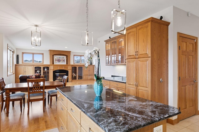 kitchen featuring decorative light fixtures, a glass covered fireplace, glass insert cabinets, and a center island