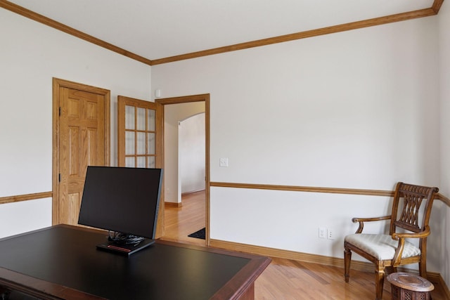 unfurnished office featuring arched walkways, wood finished floors, baseboards, and ornamental molding