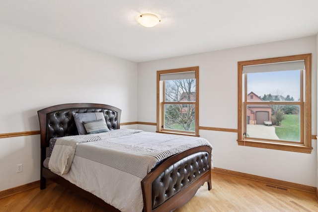 bedroom featuring light wood-type flooring, visible vents, and baseboards