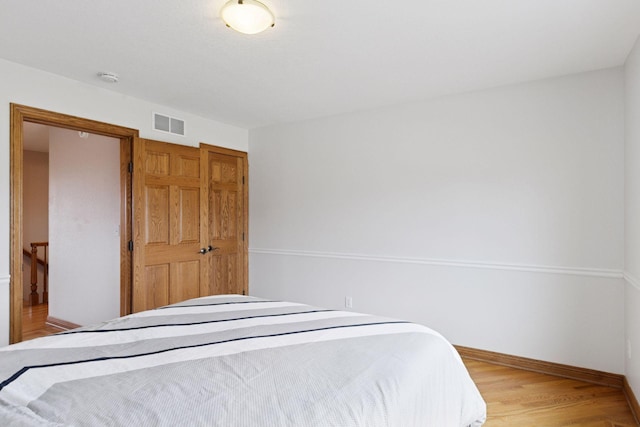 bedroom with wood finished floors, visible vents, and baseboards