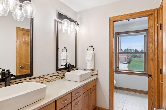 bathroom with toilet, tasteful backsplash, a sink, and double vanity