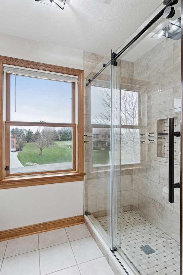 full bath with a stall shower, baseboards, and a healthy amount of sunlight