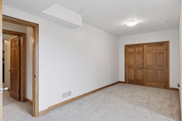 unfurnished bedroom featuring baseboards, visible vents, and light colored carpet
