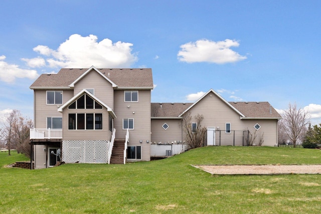 rear view of house with a sunroom, a yard, and stairs