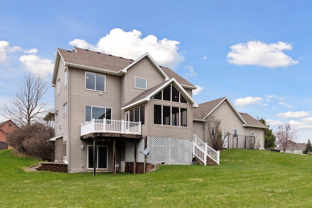 back of property featuring a lawn, a shingled roof, a sunroom, and a wooden deck