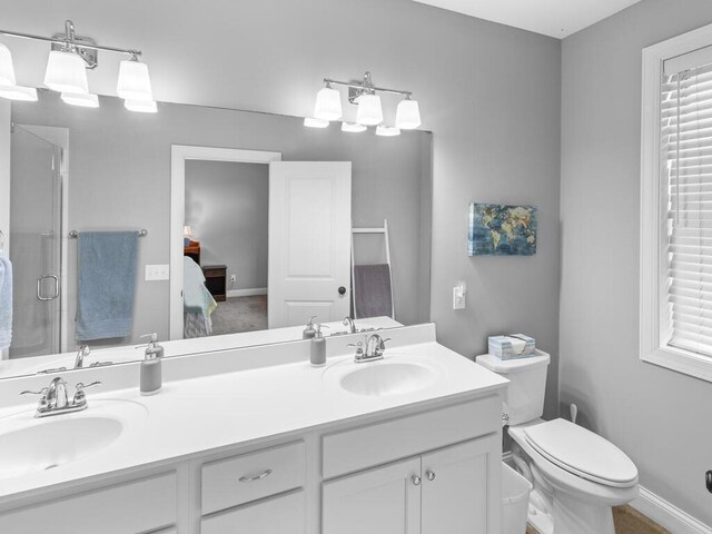 1128 Willowbrook Cir, Delano, MN 55328 - ensuite bathroom featuring double vanity, a shower stall, toilet, and baseboards