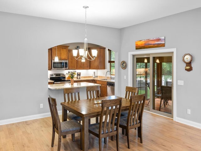 1128 Willowbrook Cir, Delano, MN 55328 - dining space with a chandelier, arched walkways, light wood-style flooring, and plenty of natural light