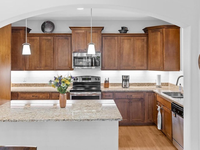 1128 Willowbrook Cir, Delano, MN 55328 - kitchen featuring appliances with stainless steel finishes, a sink, light stone countertops, light wood-style floors, and decorative light fixtures