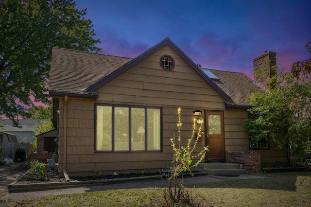 rear view of property featuring a shingled roof and a chimney