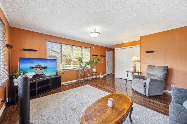 living room with wood finished floors, a textured ceiling, and baseboards