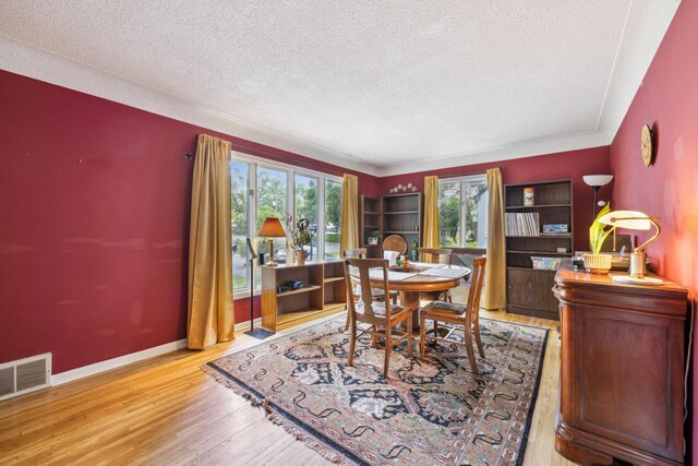 dining space featuring a textured ceiling, wood finished floors, and baseboards