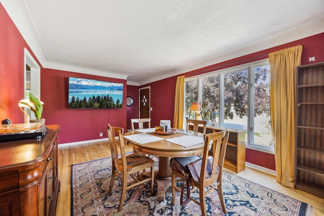 dining area with a textured ceiling, light wood-style floors, and baseboards