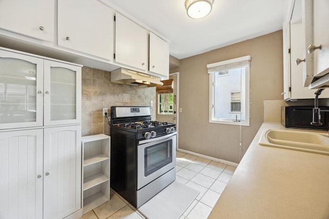kitchen with stainless steel range with gas cooktop, under cabinet range hood, white cabinets, light countertops, and light tile patterned floors