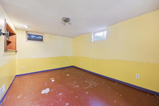below grade area with baseboards and a textured ceiling