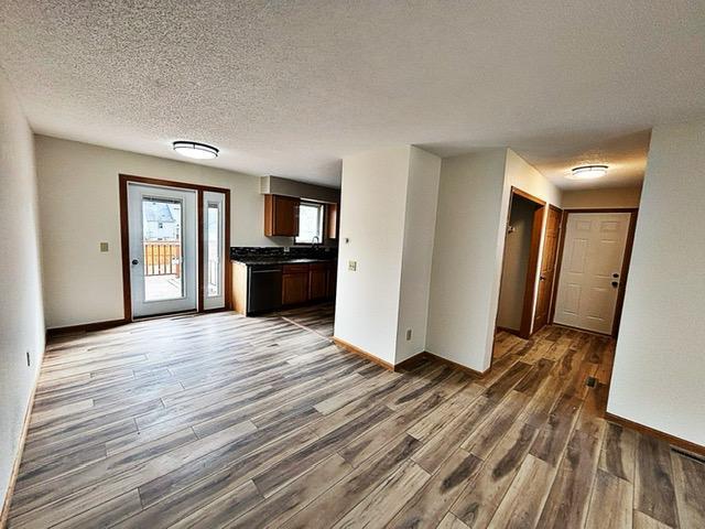 unfurnished living room with a textured ceiling, baseboards, and dark wood-style floors