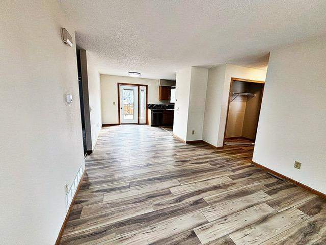 unfurnished living room with a textured ceiling, visible vents, and wood finished floors