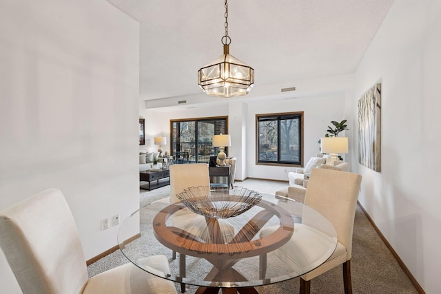 1235 Yale Pl Unit 207, Minneapolis, MN 55403 - dining area featuring light colored carpet, baseboards, a notable chandelier, and visible vents