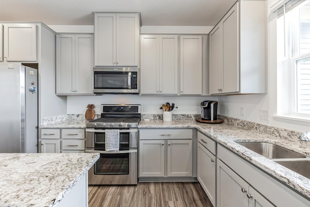 6432 Genevieve Trl S, Cottage Grove, MN 55016 - kitchen featuring gray cabinets, appliances with stainless steel finishes, light stone countertops, a sink, and light wood finished floors