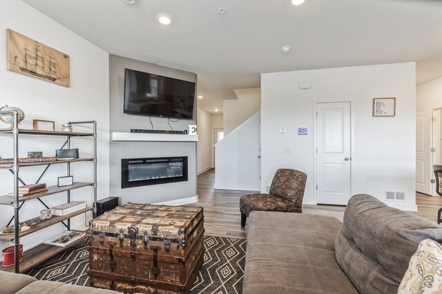 6432 Genevieve Trl S, Cottage Grove, MN 55016 - living area featuring visible vents, wood finished floors, baseboards, a glass covered fireplace, and recessed lighting