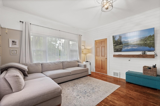 living area featuring wood finished floors, visible vents, and ornamental molding