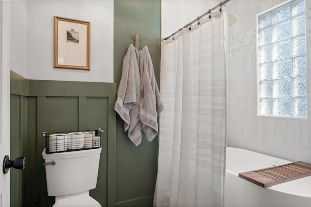 bathroom with a tub, curtained shower, and toilet