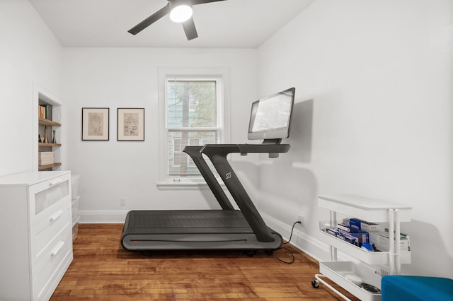 exercise room with a ceiling fan, wood finished floors, and baseboards