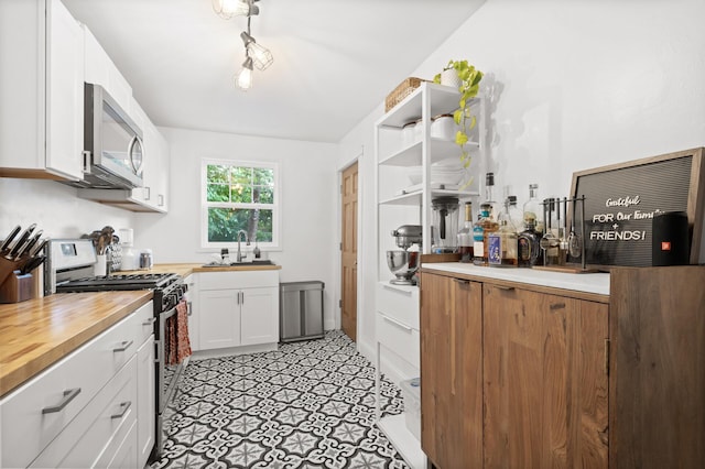 kitchen with white cabinetry, wooden counters, appliances with stainless steel finishes, and a sink