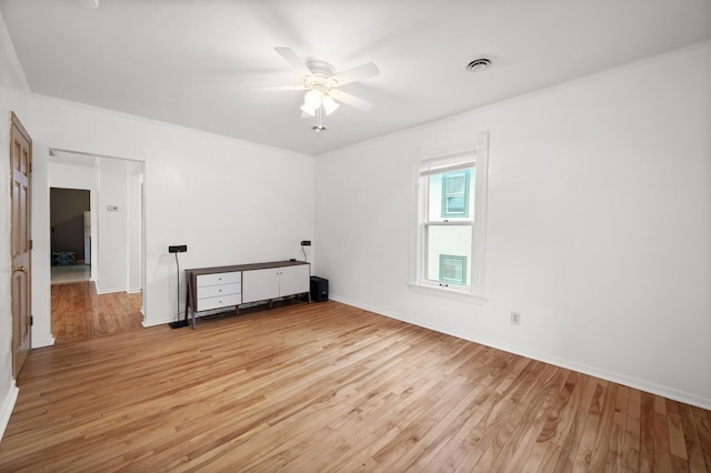 empty room with ceiling fan, visible vents, light wood-style flooring, and ornamental molding
