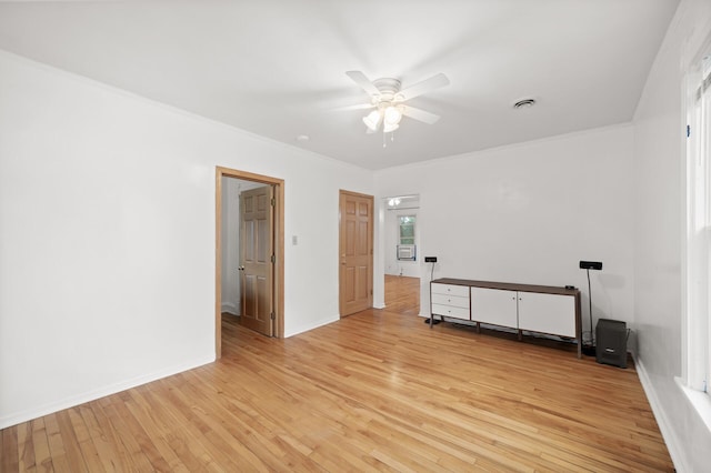spare room with visible vents, crown molding, baseboards, light wood-style flooring, and a ceiling fan