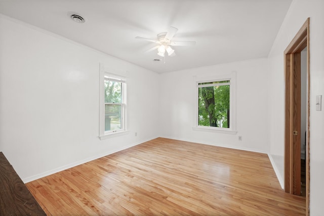 spare room with light wood finished floors, visible vents, baseboards, and ceiling fan