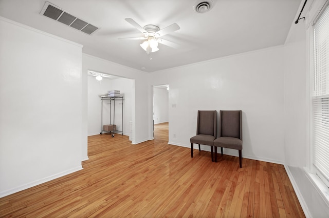sitting room with ornamental molding, a ceiling fan, visible vents, and light wood-type flooring