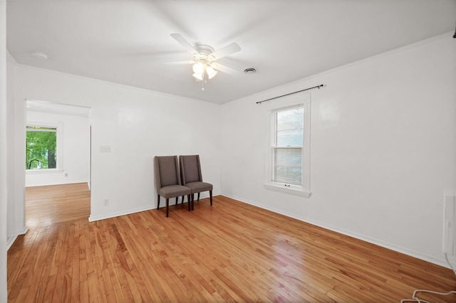 sitting room with baseboards, plenty of natural light, light wood-style flooring, and a ceiling fan