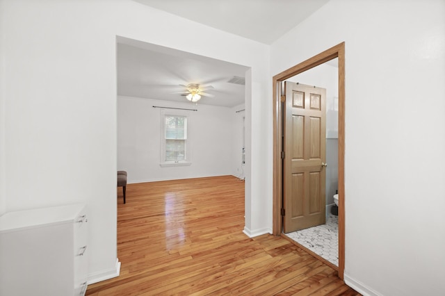 hallway with visible vents, light wood-type flooring, and baseboards