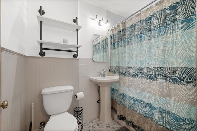 full bathroom with a wainscoted wall, curtained shower, toilet, and tile patterned flooring