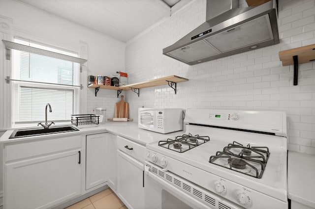 kitchen featuring white appliances, open shelves, a sink, light countertops, and wall chimney range hood