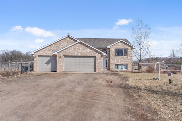 view of front of house featuring brick siding, dirt driveway, an attached garage, and fence